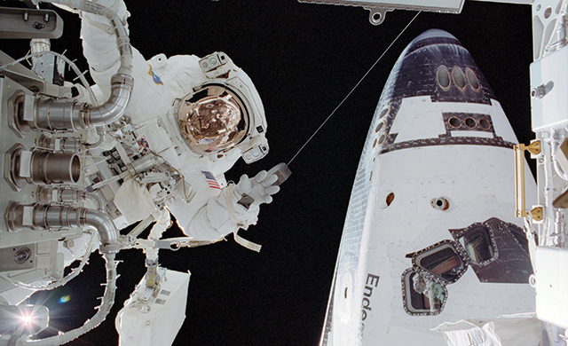 John Herrington can be seen on one of his EVA's on the International Space Station.  The shuttle Endeavour located behind him is docked to the ISS.