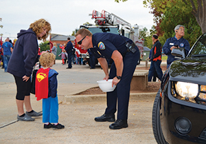 Child trick-or-treating with police officer at the Downtown Edmond Old Fashioned Festival
